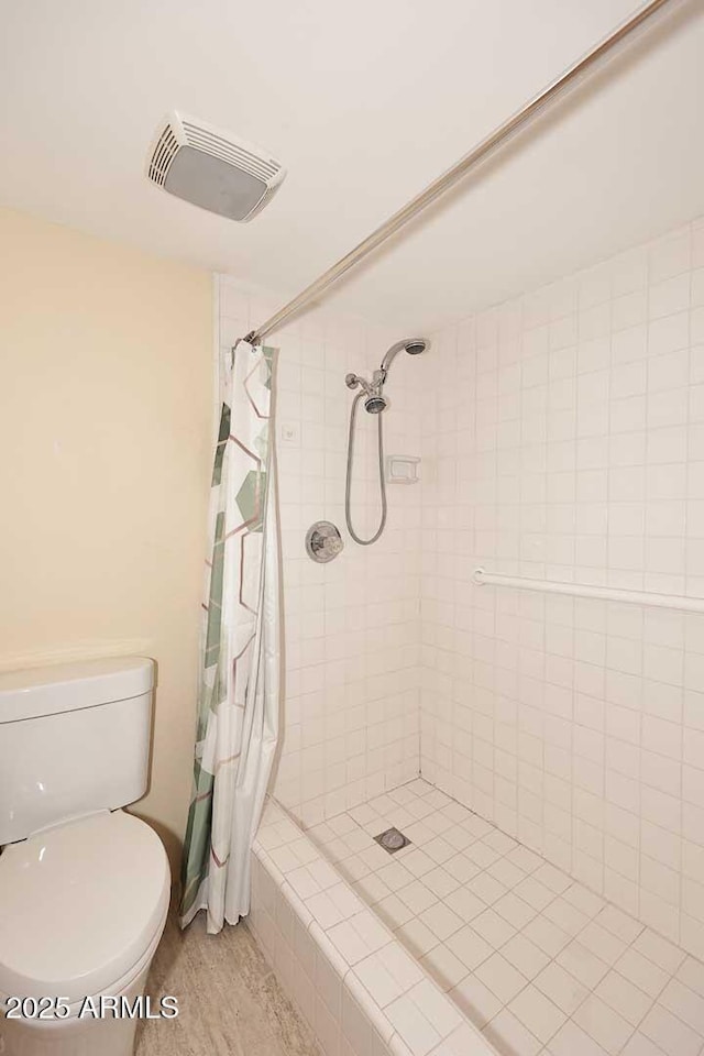 bathroom featuring toilet, visible vents, and tiled shower