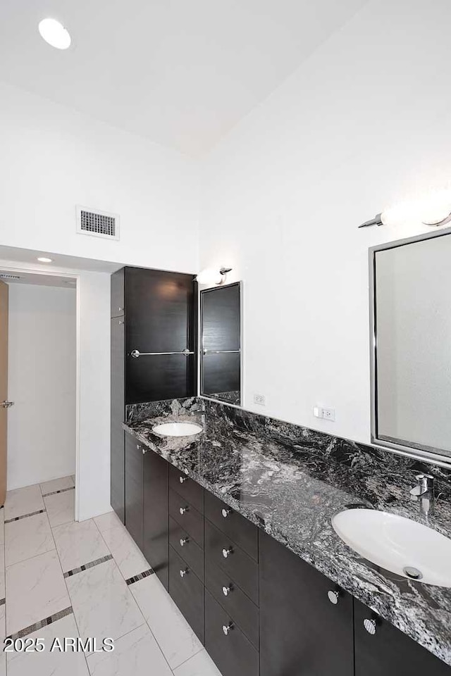 bathroom with marble finish floor, visible vents, a sink, and double vanity