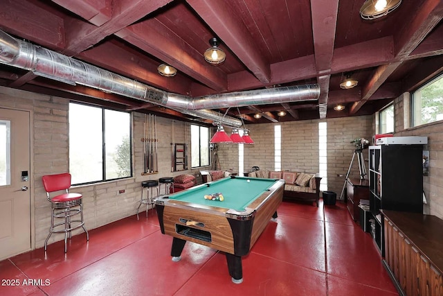 rec room featuring plenty of natural light, finished concrete flooring, and brick wall