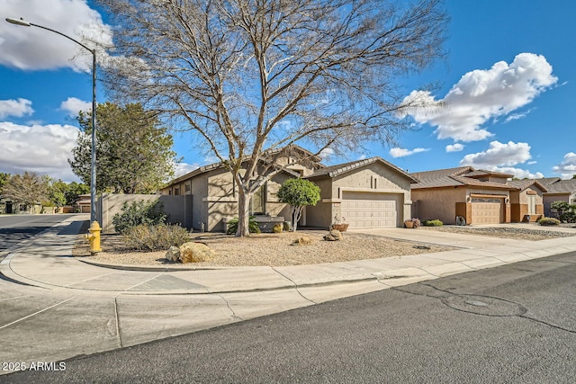 view of front facade with concrete driveway, a tile roof, an attached garage, fence, and stucco siding