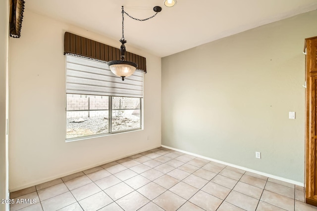 empty room with baseboards and light tile patterned floors