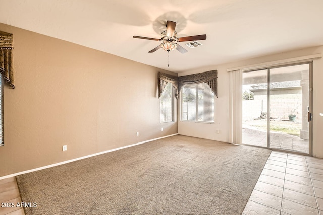 carpeted spare room with baseboards, tile patterned flooring, visible vents, and a ceiling fan