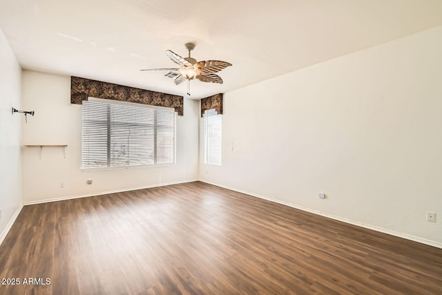 spare room with ceiling fan, dark wood-style floors, and baseboards