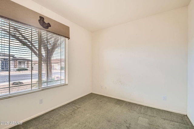 carpeted empty room featuring baseboards