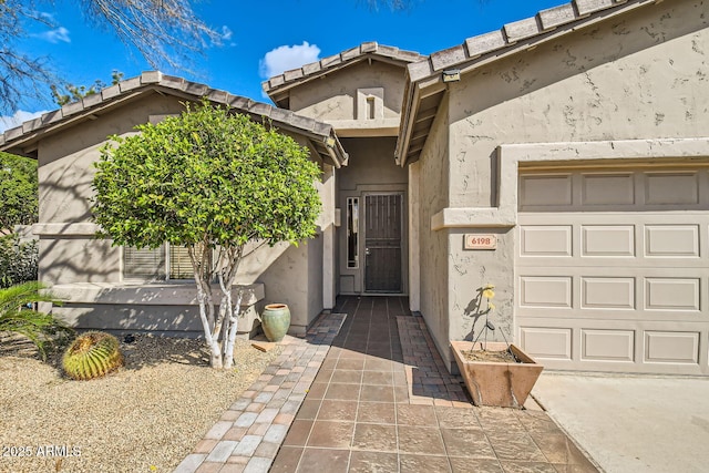 property entrance with an attached garage and stucco siding