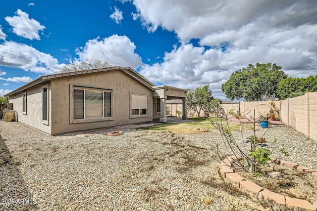 rear view of house with a fenced backyard and stucco siding