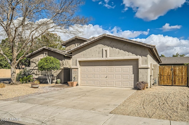 view of front facade with concrete driveway, an attached garage, fence, and stucco siding