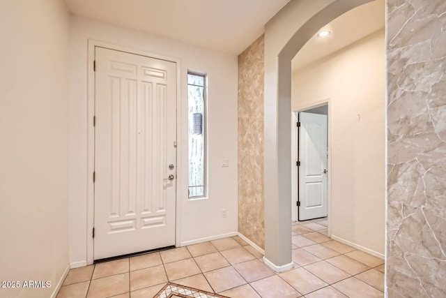 foyer with arched walkways, light tile patterned floors, and a healthy amount of sunlight