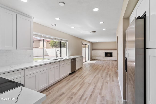 kitchen featuring white cabinetry, light wood finished floors, appliances with stainless steel finishes, and a sink