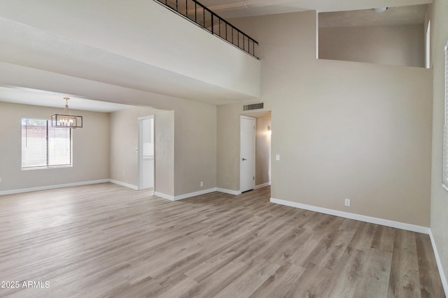 empty room featuring visible vents, baseboards, light wood-style floors, and an inviting chandelier