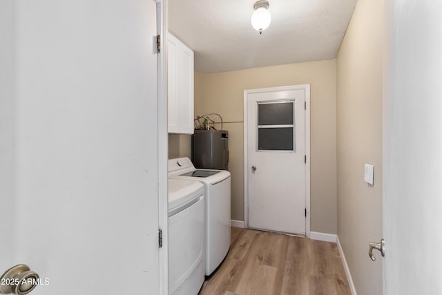 laundry room featuring light wood-type flooring, washer and clothes dryer, water heater, cabinet space, and baseboards