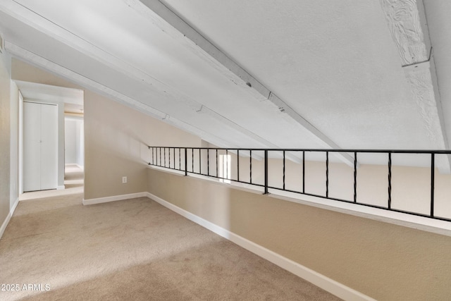 hallway featuring lofted ceiling, carpet, and baseboards