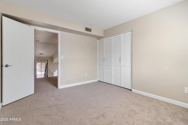 unfurnished bedroom featuring carpet, visible vents, a closet, and baseboards