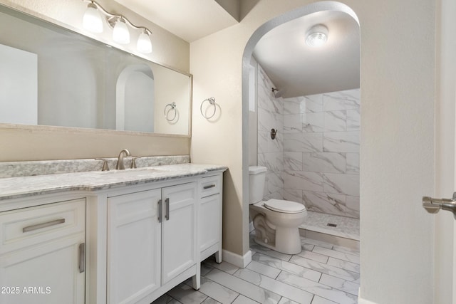 bathroom featuring tiled shower, marble finish floor, vanity, and toilet