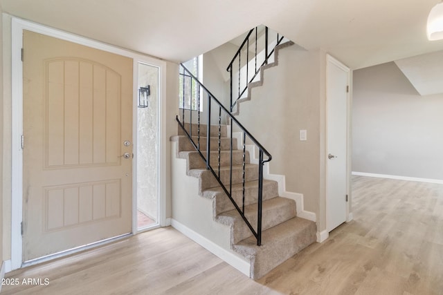 foyer entrance featuring stairway, wood finished floors, and baseboards