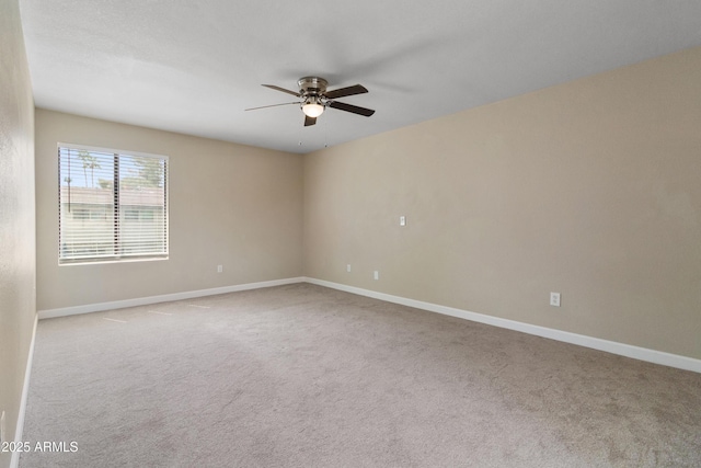 carpeted spare room featuring baseboards and ceiling fan