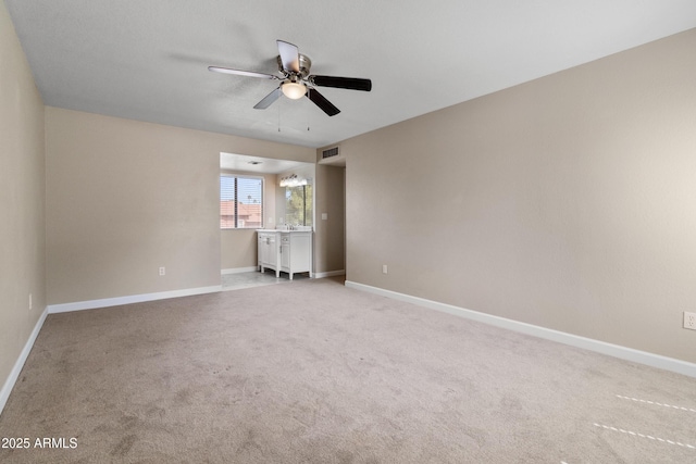 carpeted spare room featuring visible vents, baseboards, and ceiling fan