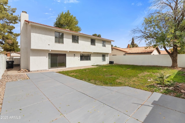 back of property with stucco siding, a patio, a fenced backyard, a yard, and a chimney