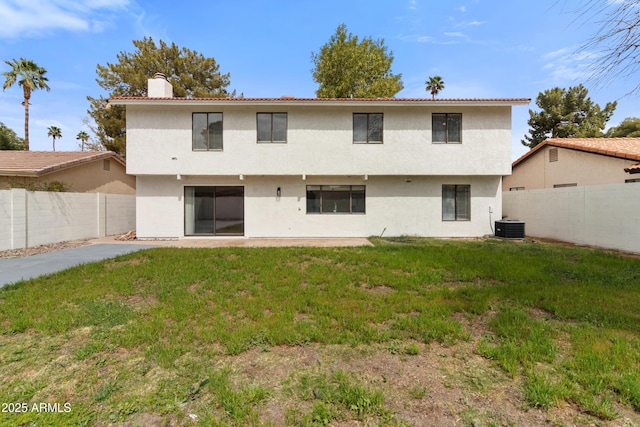 back of property with a fenced backyard, central AC, stucco siding, a chimney, and a lawn