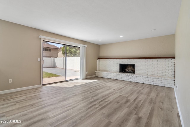 unfurnished living room featuring recessed lighting, a brick fireplace, baseboards, and wood finished floors