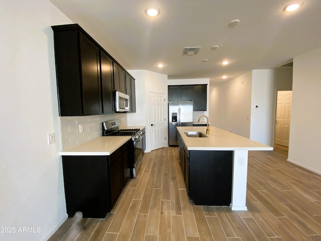 kitchen with wood tiled floor, decorative backsplash, stainless steel appliances, and a sink