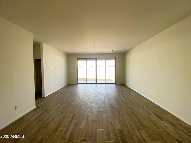 empty room with baseboards and dark wood-type flooring