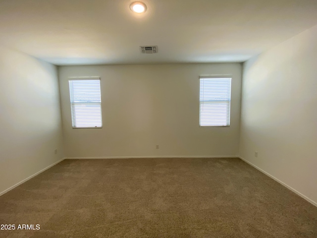 spare room with carpet, visible vents, and baseboards