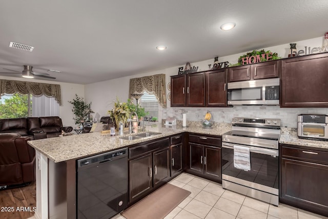 kitchen featuring backsplash, open floor plan, a peninsula, stainless steel appliances, and a sink