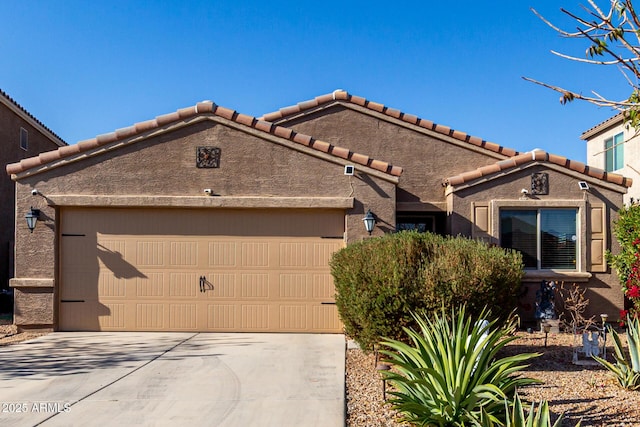 view of front of property featuring concrete driveway, a tiled roof, an attached garage, and stucco siding