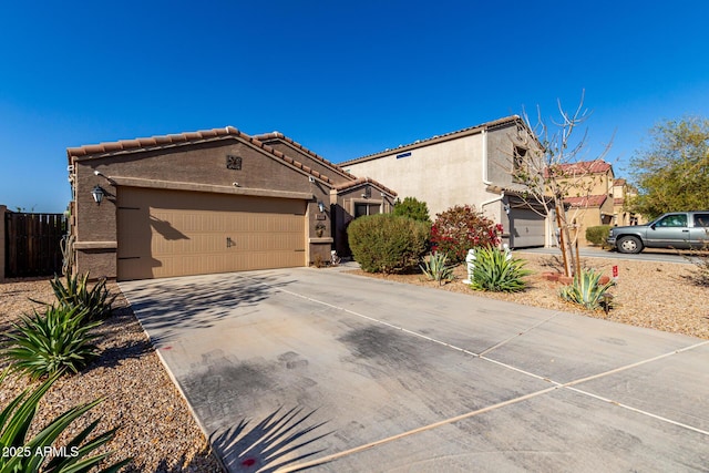 view of front of house with an attached garage, fence, a tiled roof, stucco siding, and driveway