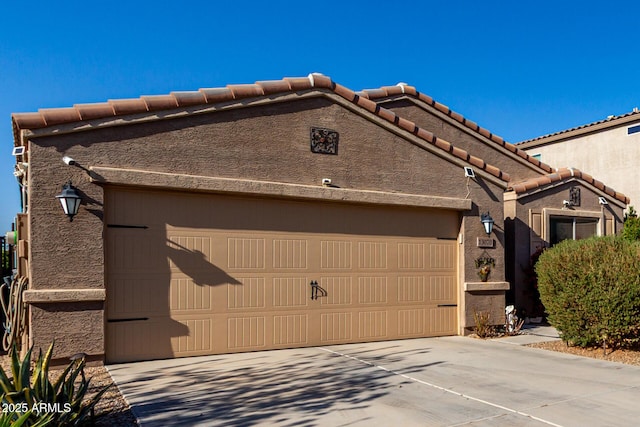 exterior space featuring stucco siding, driveway, an attached garage, and a tile roof