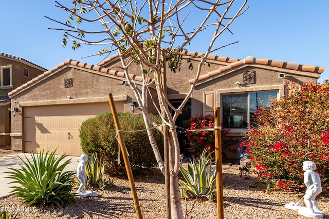 view of front of home with a garage, stucco siding, and a tiled roof