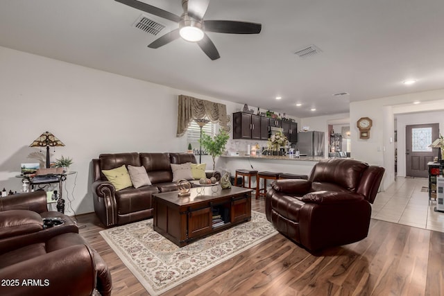 living room featuring a ceiling fan, recessed lighting, light wood-style floors, and visible vents