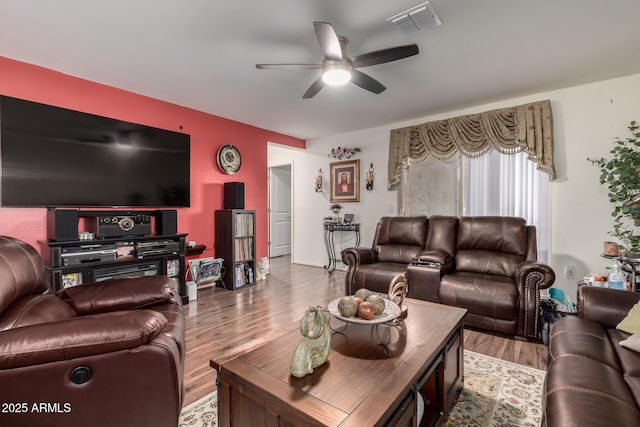 living area with visible vents, a ceiling fan, and wood finished floors