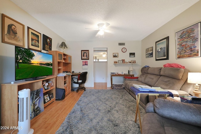 living area with light wood-style flooring, visible vents, ceiling fan, and a textured ceiling