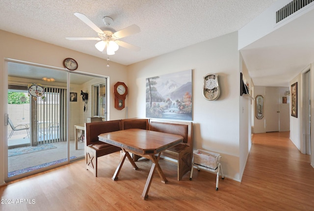 dining area featuring a ceiling fan, visible vents, light wood-style flooring, and a textured ceiling