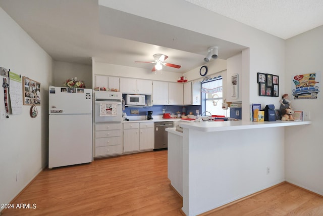 kitchen featuring light wood-style flooring, a peninsula, white appliances, white cabinetry, and light countertops