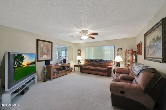 living area featuring carpet floors, ceiling fan, and a textured ceiling