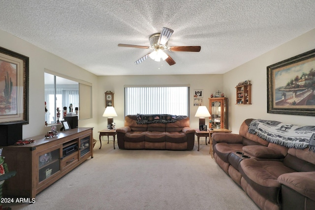 living area featuring light colored carpet, ceiling fan, and a textured ceiling