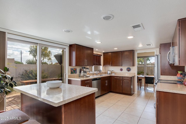 kitchen with sink, light tile patterned floors, stainless steel appliances, dark brown cabinetry, and a kitchen island