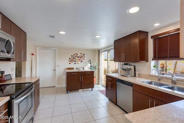 kitchen with sink, stainless steel appliances, a textured ceiling, and light tile patterned flooring