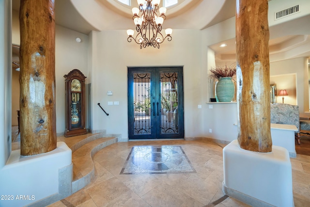 entrance foyer with a chandelier, french doors, and a tray ceiling