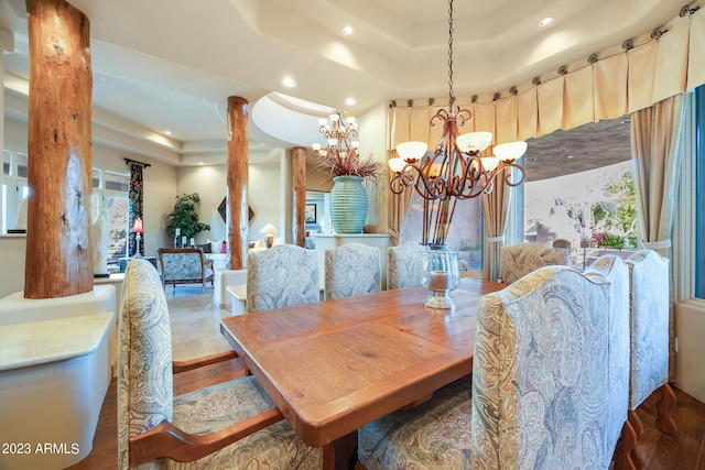 dining area with hardwood / wood-style floors, a tray ceiling, and an inviting chandelier