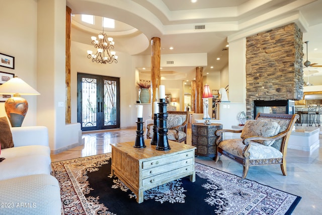 living room featuring a fireplace, a towering ceiling, light tile patterned flooring, and ceiling fan with notable chandelier