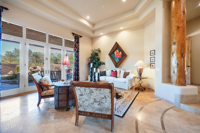 living room featuring a raised ceiling, a high ceiling, and french doors