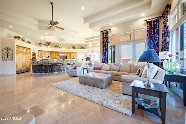 living room with ceiling fan with notable chandelier and a raised ceiling