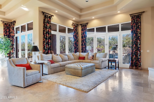 living room with a tray ceiling, french doors, a healthy amount of sunlight, and a high ceiling