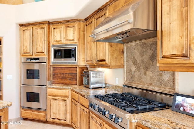 kitchen with decorative backsplash, light tile patterned flooring, wall chimney range hood, and appliances with stainless steel finishes