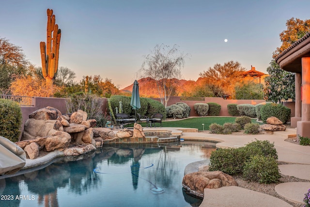 pool at dusk with an in ground hot tub