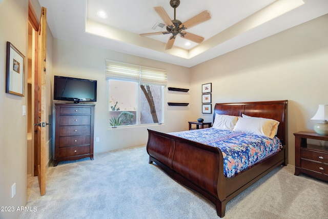 bedroom with a tray ceiling, ceiling fan, and light carpet